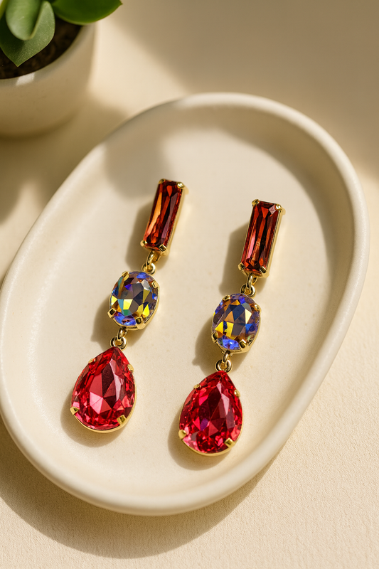 Korean statement jewel drop earrings with red gemstone, multicolor crystal, and teardrop red gem in a gold setting on a beige tray.