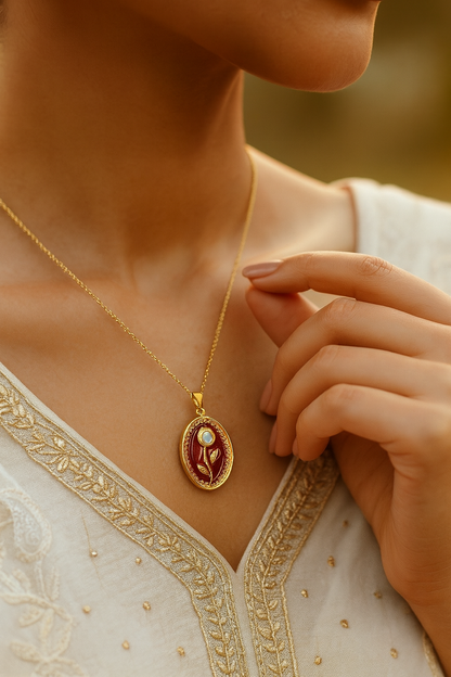 Gold necklace with an oval red pendant featuring a white rose.
