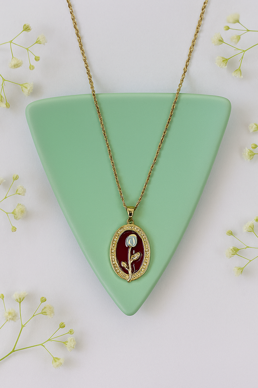 Gold necklace with an oval red pendant featuring a white rose.